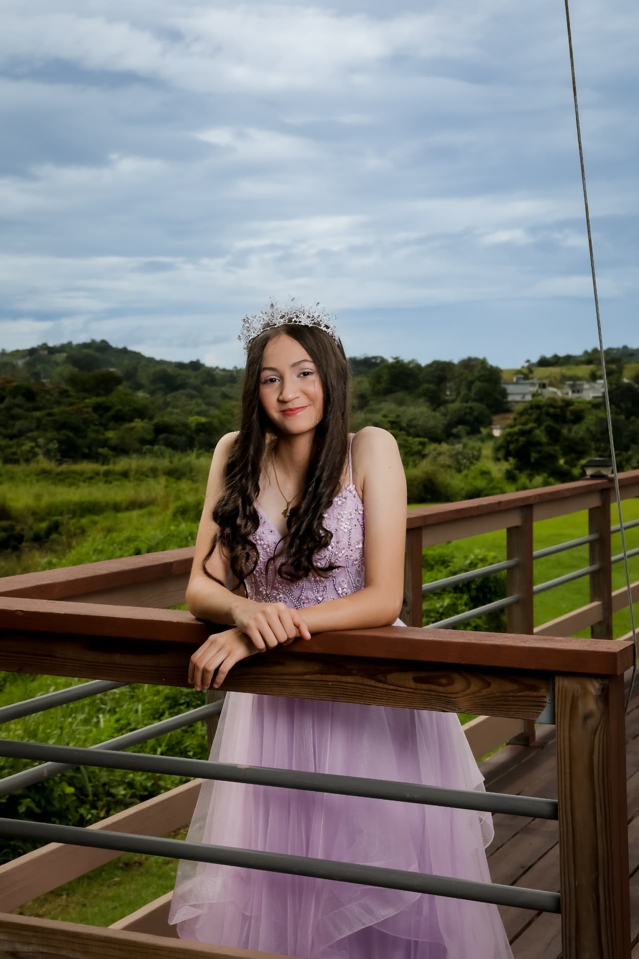 Quinceañera con vestido lila y corona en una terraza al aire libre