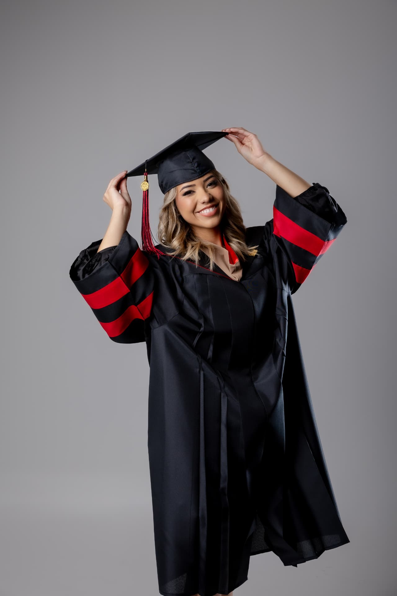 Graduanda sonriente con toga negra y detalles rojos