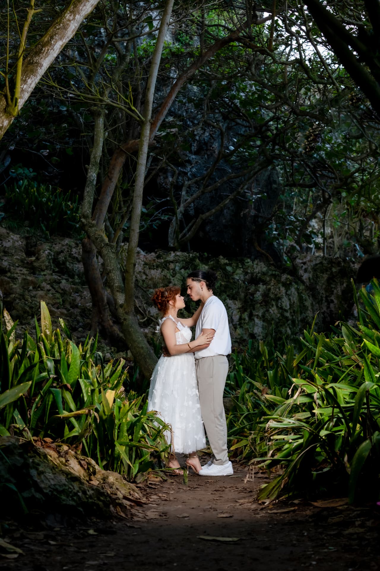 Pareja abrazada en sendero rodeado de vegetación y árboles